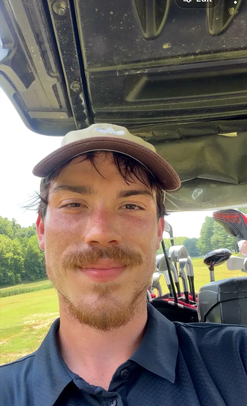 Hunter sitting in a golf cart on a golf course.